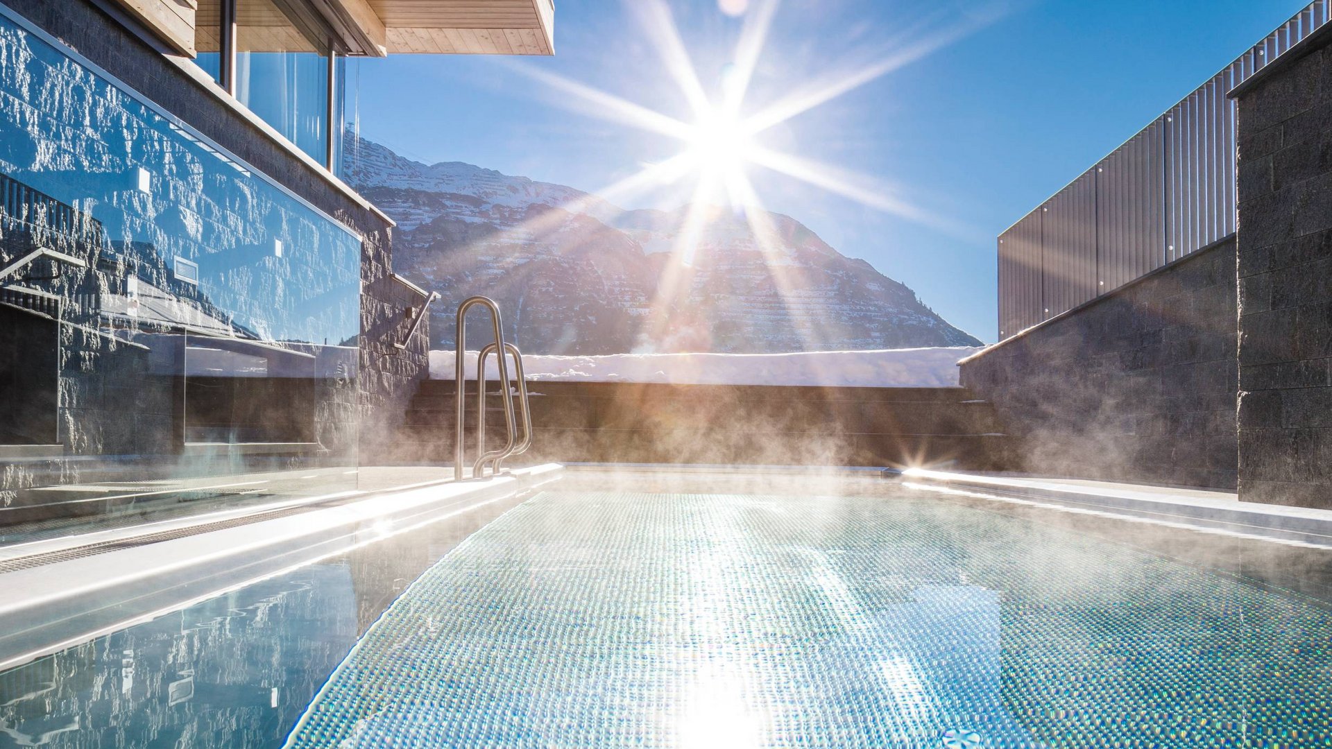 Ihr Apartment in Lech am Arlberg. Ruhe, Raum und Freiheit. Dampfendes Schwimmbad mit Bergsicht und strahlender Sonne